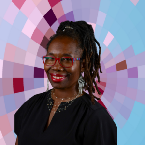 Headshot of Kim Fox, a smiling Black woman with red glasses and hair in locks, wearing a dark top and a necklace and earrings on top of a MYFest background of colorful pink, purple and blue four-sided shapes spiraling out from the center.