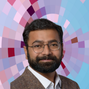 Headshot of Anuj Gupta, a smiling man with short dark hair and trimmed beard and mustache wearing a white shirt, light-brown suit jacket, and wire-rim eyeglasses on top of a MYFest background of colorful pink, purple and blue four-sided shapes spiraling out from the center.