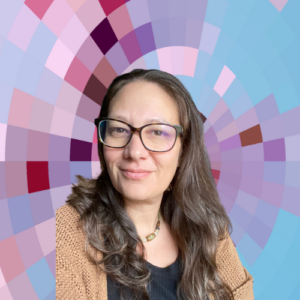Headshot of Hannah Grossman, a smiling white woman with long brown hair wearing a dark top, light-brown sweater, dark-framed eyeglasses, and a necklace of oblong roundish beads or stones on top of a MYFest background of colorful pink, purple and blue four-sided shapes spiraling out from the center.